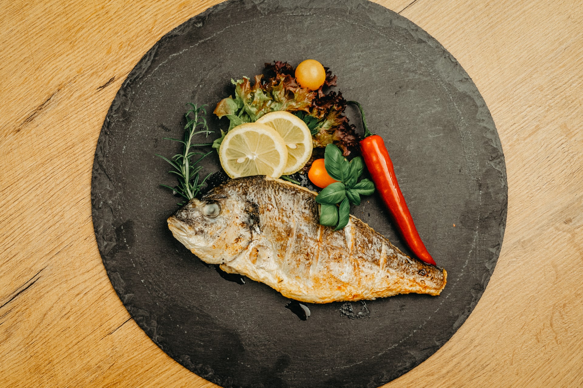 Fisch angerichtet auf Platte mit Zitrone und Chili